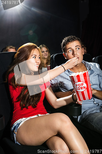 Image of Woman Feeding Popcorn To Boyfriend In Theatre