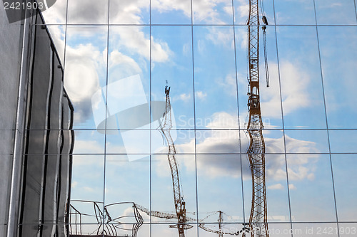 Image of Construction cranes reflecting in a modern building