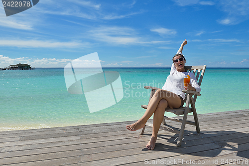 Image of Beautiful young woman with a drink by the sea