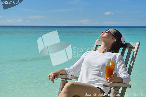 Image of Beautiful young woman with a drink by the sea