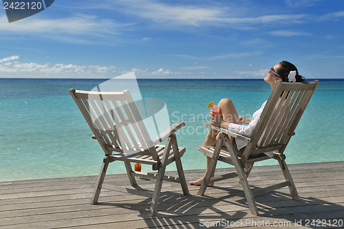 Image of Beautiful young woman with a drink by the sea