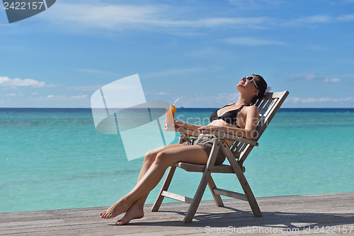 Image of Beautiful young woman with a drink by the sea