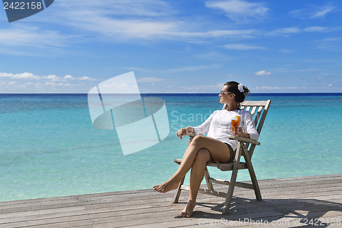 Image of Beautiful young woman with a drink by the sea