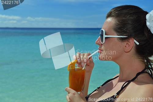 Image of Beautiful young woman with a drink by the sea