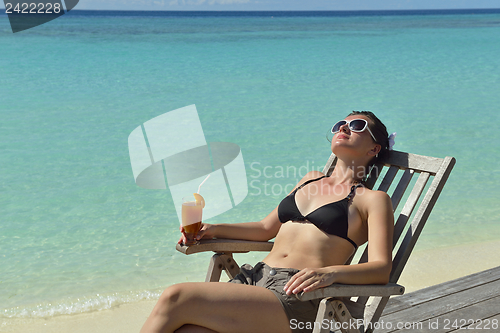 Image of Beautiful young woman with a drink by the sea