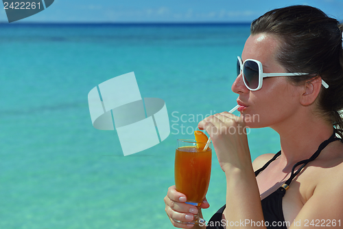 Image of Beautiful young woman with a drink by the sea