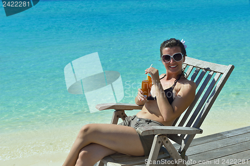 Image of Beautiful young woman with a drink by the sea