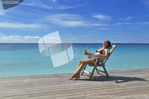 Image of Beautiful young woman with a drink by the sea
