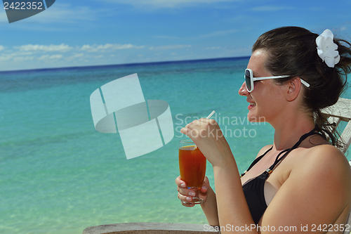 Image of Beautiful young woman with a drink by the sea