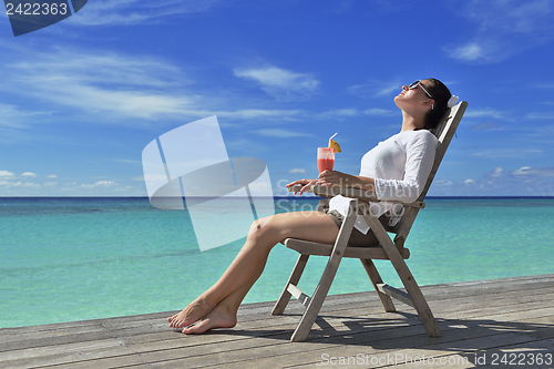 Image of Beautiful young woman with a drink by the sea