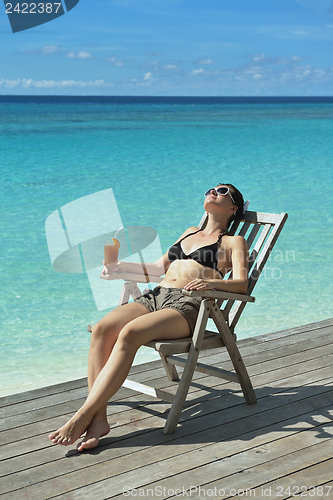 Image of Beautiful young woman with a drink by the sea