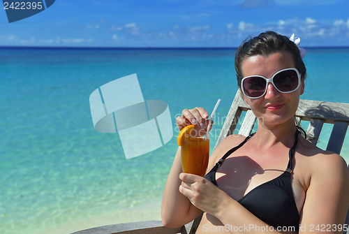 Image of Beautiful young woman with a drink by the sea