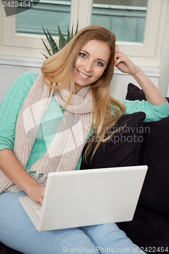 Image of smiling woman on couch with notebook