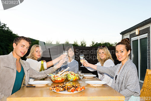 Image of Friends Toasting Drinks At Table During Outdoor Party