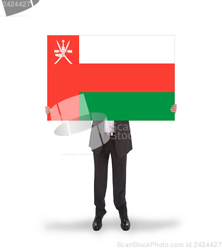 Image of Businessman holding a big card, flag of Oman