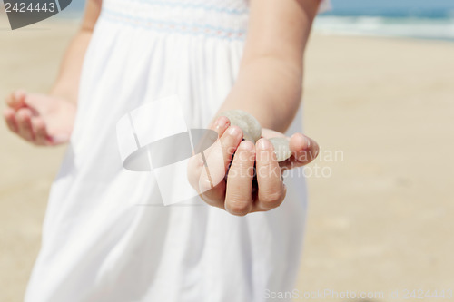 Image of Girl on the beach holding stones