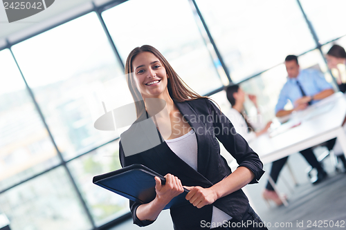 Image of business woman with her staff in background at office