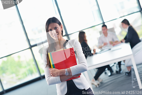 Image of business woman with her staff in background at office