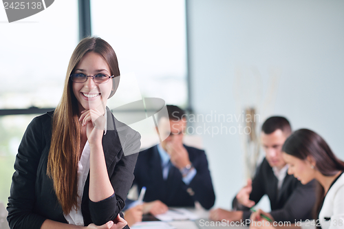 Image of business woman with her staff in background at office