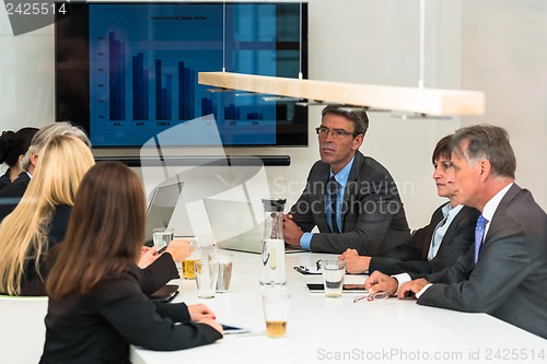 Image of Mixed group in business meeting seen through glass door