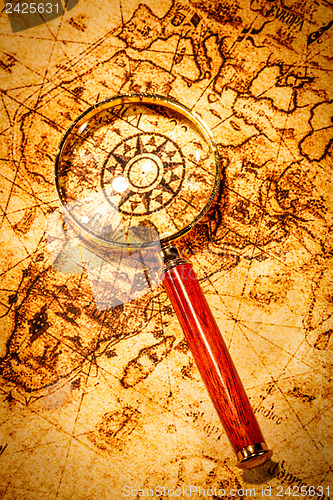 Image of Vintage magnifying glass lies on an ancient world map