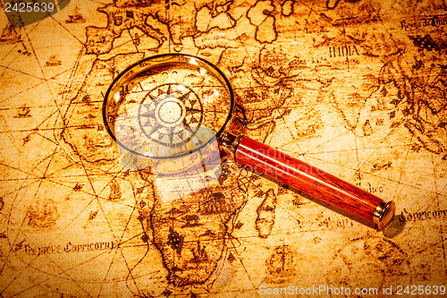 Image of Vintage magnifying glass lies on an ancient world map