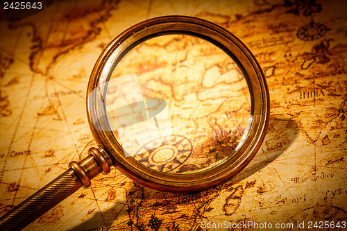 Image of Vintage magnifying glass lies on an ancient world map