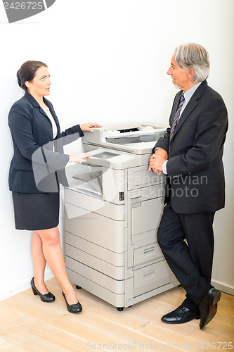 Image of Colleagues talking at  copying machine in the office