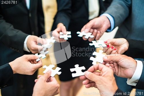 Image of Teamwork - Business people solving a puzzle