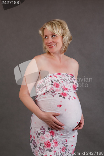 Image of beautiful pregnant woman tenderly holding her tummy isolated on white background