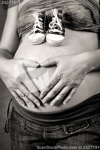 Image of pregnant woman with a child's shoe and hand heart shape