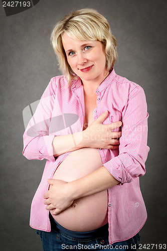 Image of beautiful pregnant woman tenderly holding her tummy