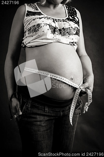 Image of pregnant woman tenderly measuring her tummy 