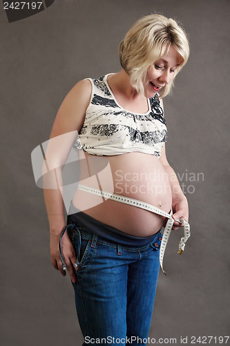 Image of beautiful pregnant woman tenderly measuring her tummy