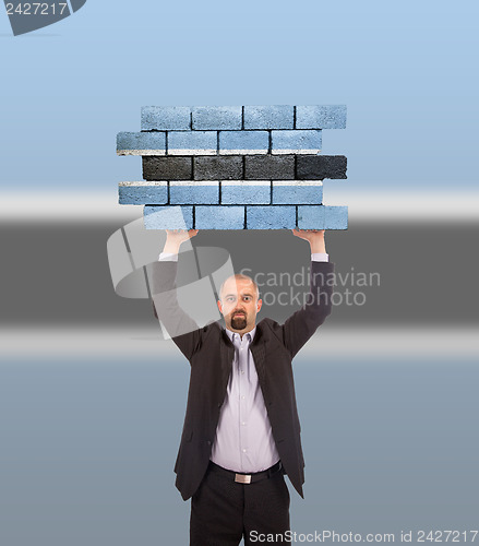 Image of Businessman holding a large piece of a brick wall