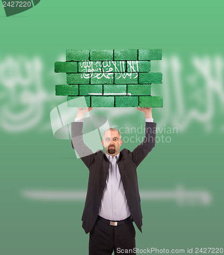 Image of Businessman holding a large piece of a brick wall