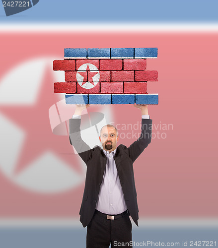 Image of Businessman holding a large piece of a brick wall