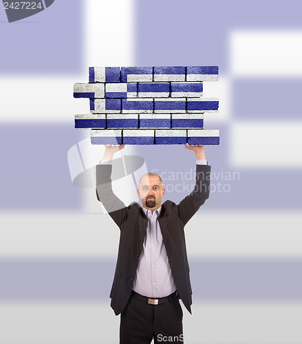 Image of Businessman holding a large piece of a brick wall