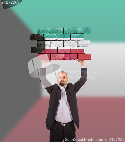 Image of Businessman holding a large piece of a brick wall