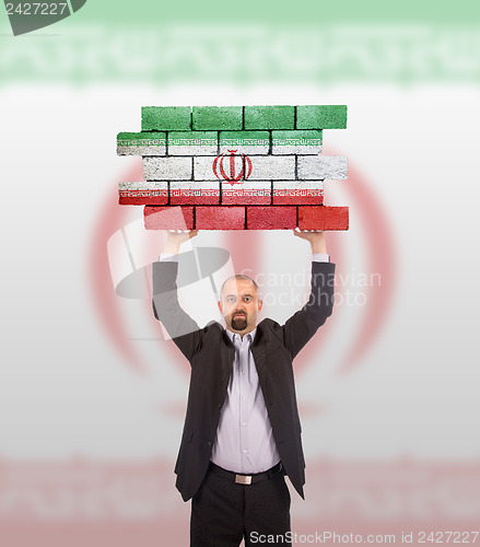 Image of Businessman holding a large piece of a brick wall