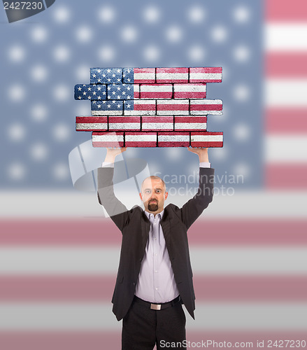 Image of Businessman holding a large piece of a brick wall