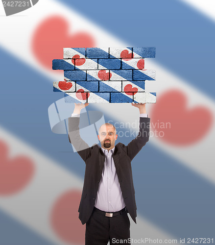 Image of Businessman holding a large piece of a brick wall