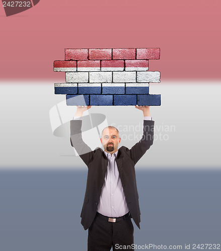 Image of Businessman holding a large piece of a brick wall