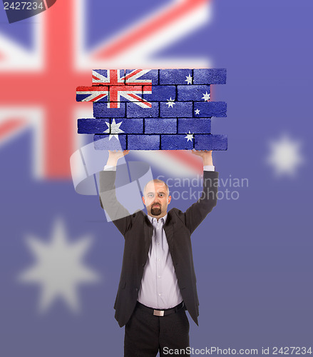 Image of Businessman holding a large piece of a brick wall