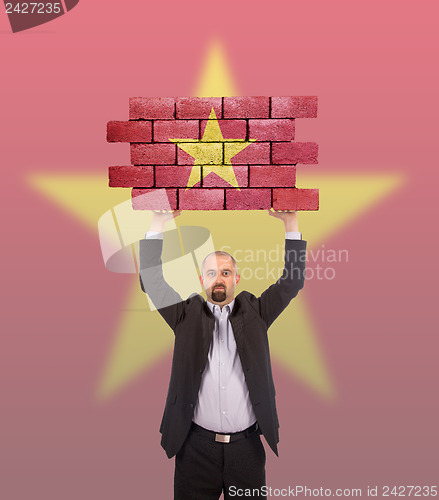 Image of Businessman holding a large piece of a brick wall