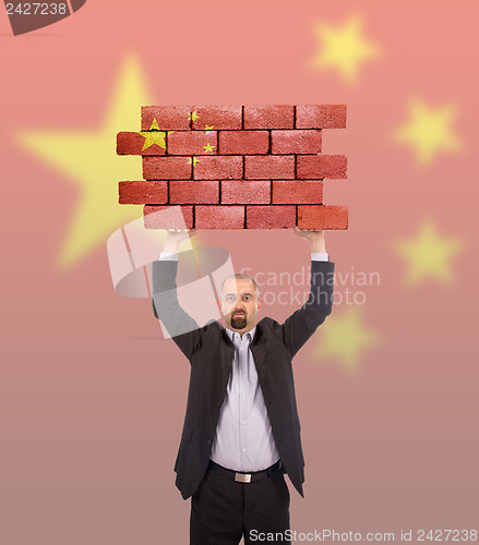 Image of Businessman holding a large piece of a brick wall