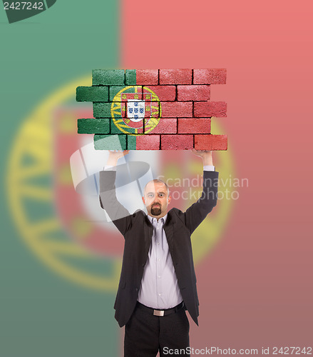 Image of Businessman holding a large piece of a brick wall