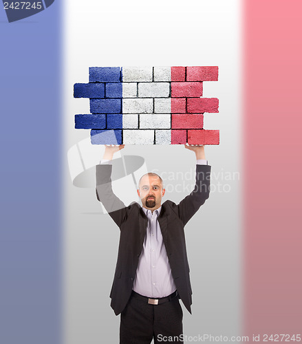 Image of Businessman holding a large piece of a brick wall