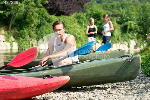 Image of Man sitting by kayak