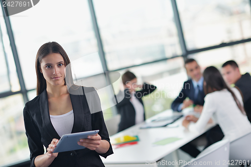 Image of business woman with her staff in background at office
